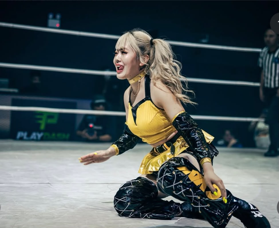 Female wrestler celebrates in the ring at APAC Wrestling Event